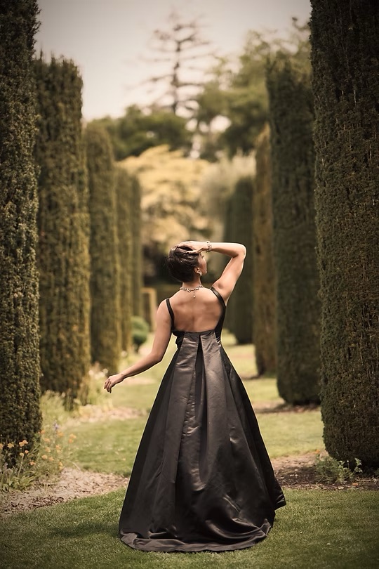 Elegant black gown in a formal garden with cypress trees